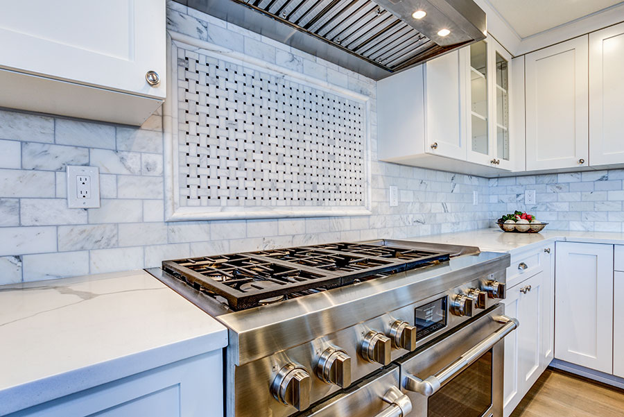 White Kitchen With Stainless Steel Hood Over Gas Cooktop